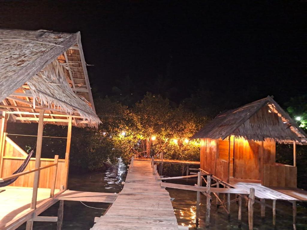 a dock with two huts on the water at night at Kombrof Homestay & Dive Center in Waisai