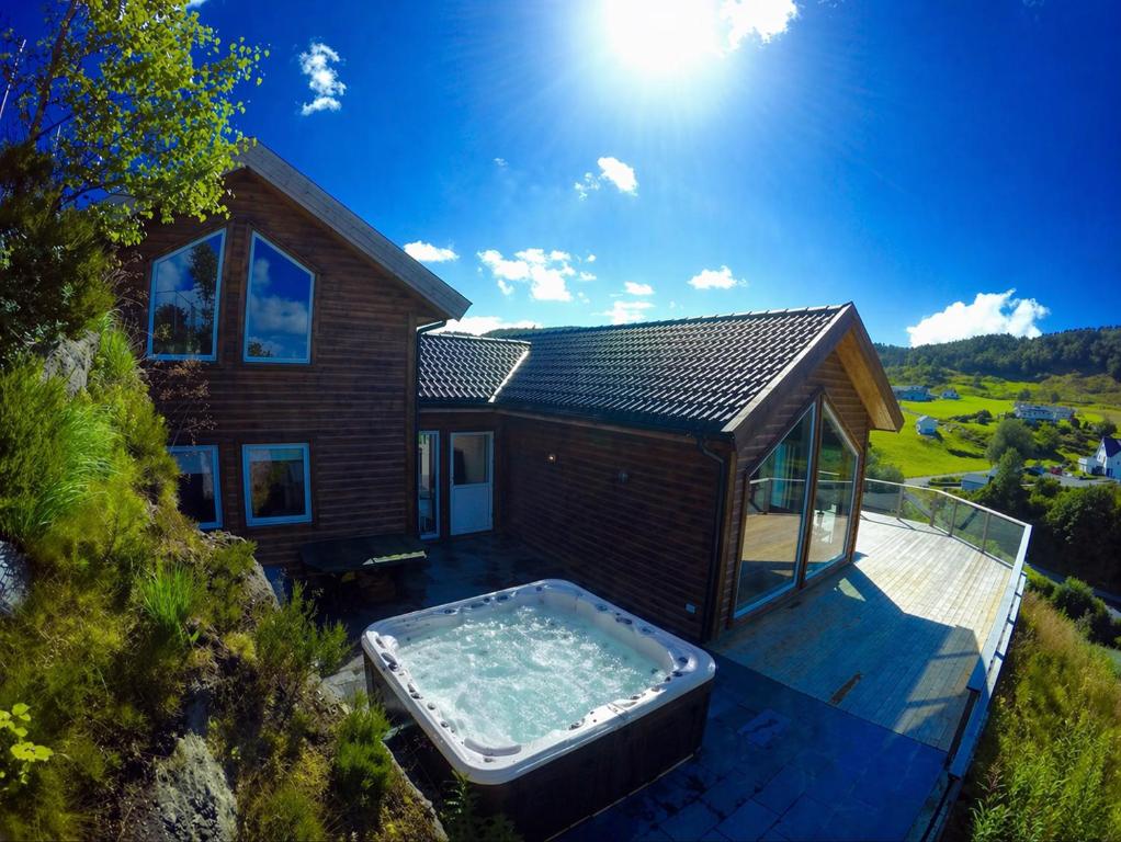 a house with a hot tub on a deck at Luxury Fjord Cabin with jacuzzi, boat dock & view in Sveio