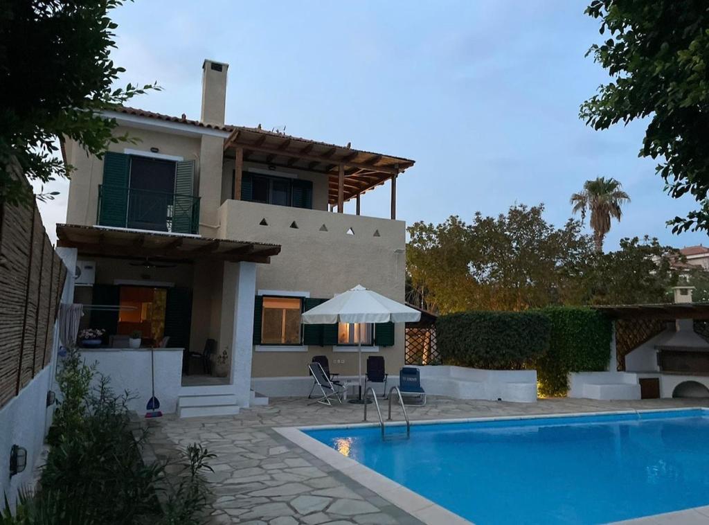 a villa with a swimming pool in front of a house at Plepi's Seaside Villa in Plépi