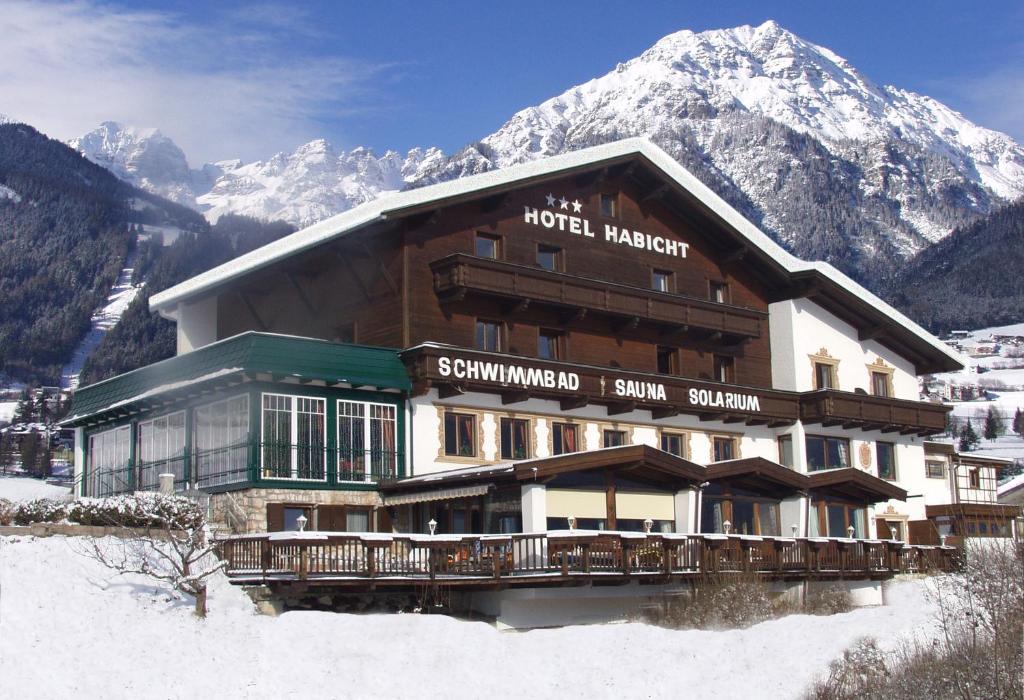 ein Hotel im Schnee vor einem Berg in der Unterkunft Hotel Habicht in Fulpmes