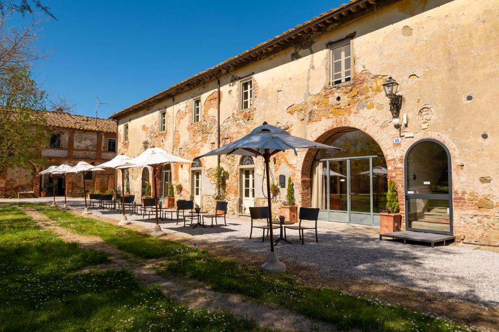 a group of tables and umbrellas in front of a building at Tenuta La Fratta in Sinalunga