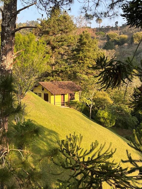 a yellow house on top of a grassy hill at Casa de campo em meio a natureza in Araras Petropolis