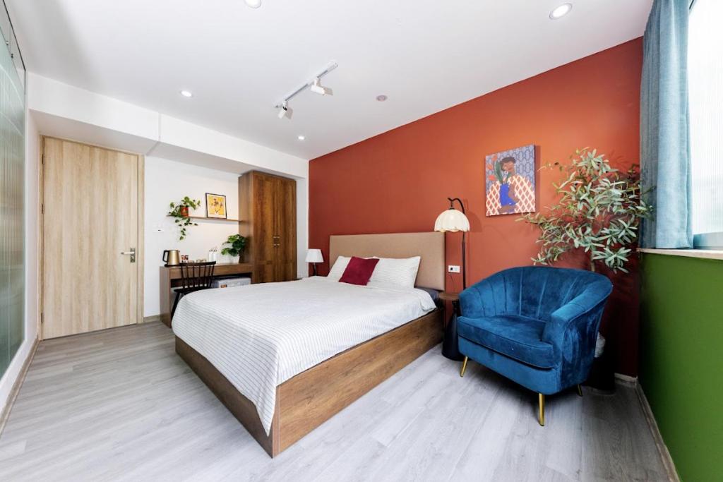 a bedroom with a bed and a blue chair at Anchie Hanoi House in Hanoi