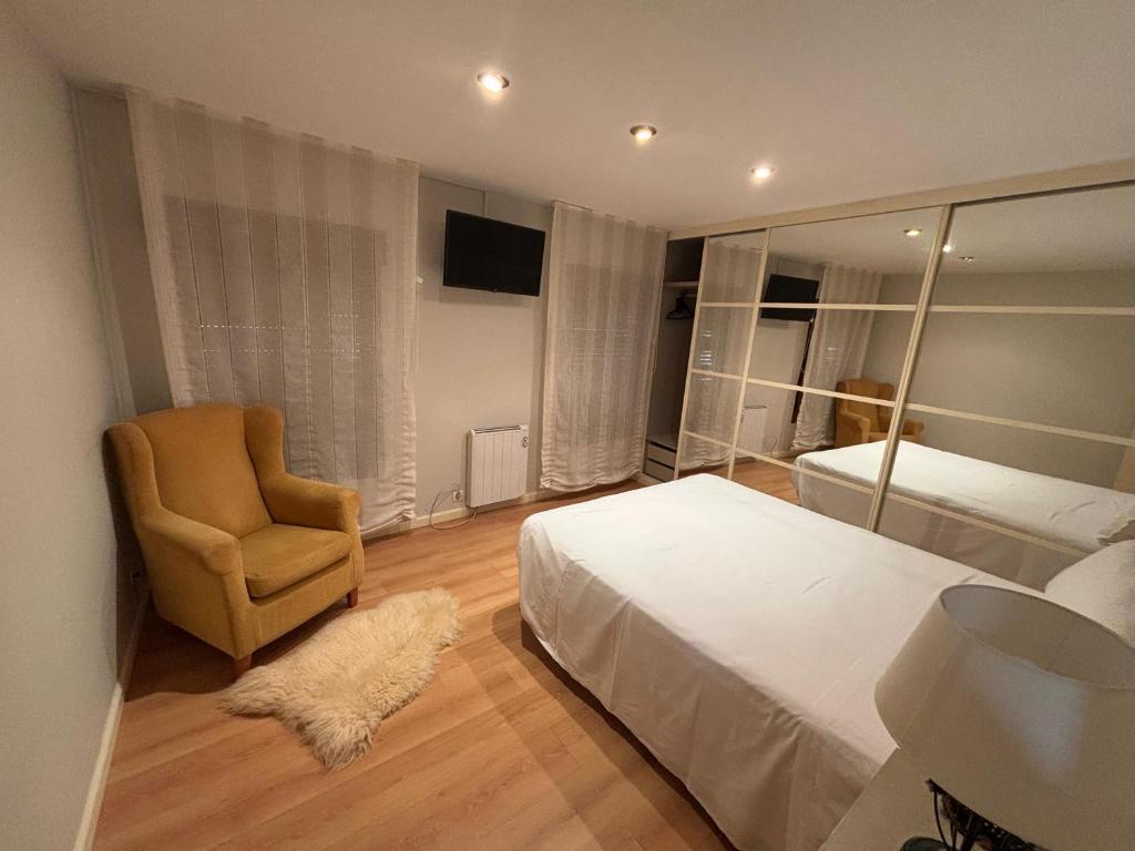 a bedroom with a bed and a chair and a mirror at Dúplex centro de Ribeira con WIFI by Cristian&Tamara"alquileres" in Ribeira