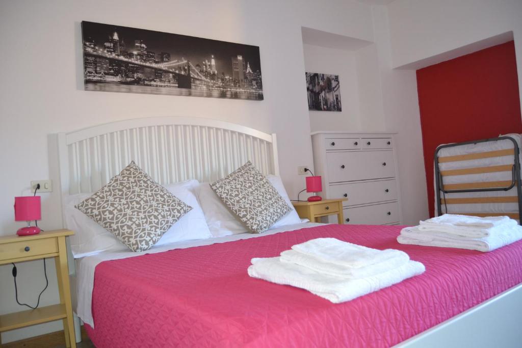 a bedroom with a pink bed with two towels on it at Casa Valentina in Brenzone sul Garda