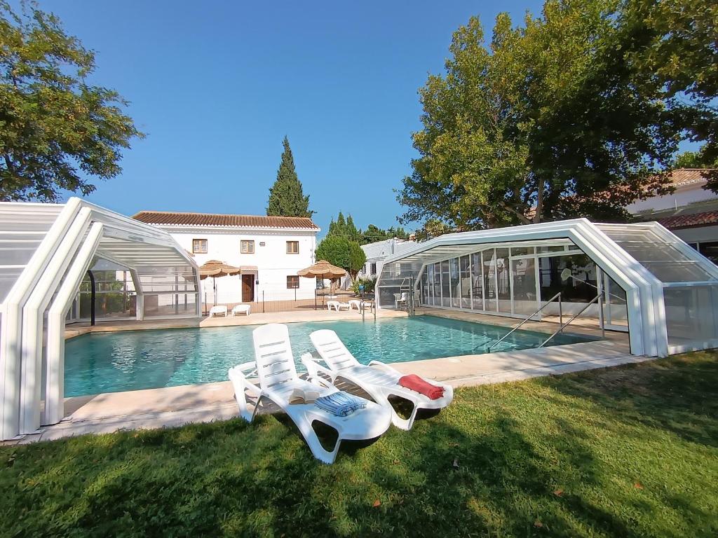 a swimming pool with two lounge chairs and a house at Embrujo Andaluz Complejo Rural Órgiva in Órgiva