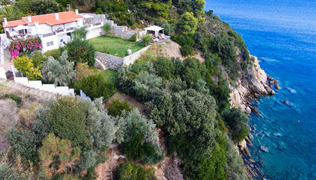 an aerial view of a house on a hill next to the ocean at Villa Bienvenue Apartments in Kanapitsa