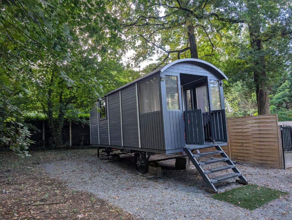 a small train car with a ladder in a yard at Roulotte enchantée in Cornillé-les-Caves