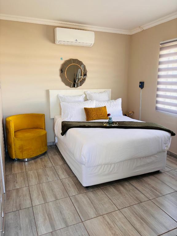 a bedroom with a large white bed and a yellow chair at Sunset Heaven in Newcastle