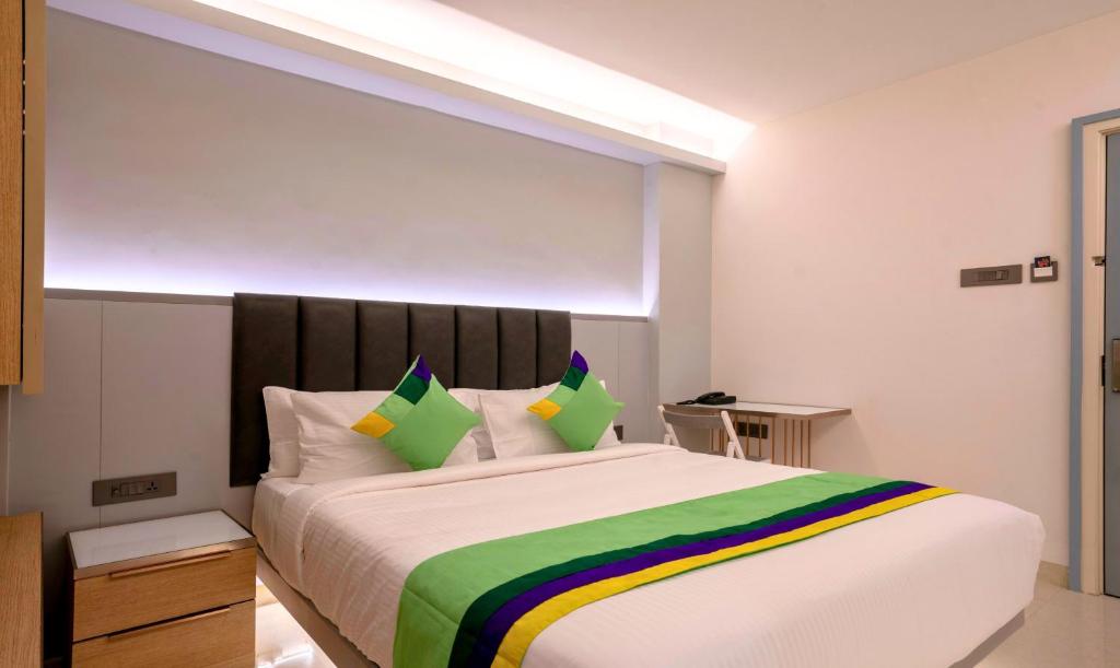 a bedroom with a large bed with green and yellow pillows at Treebo Premium D Consulate, Near US Consulate in Hyderabad
