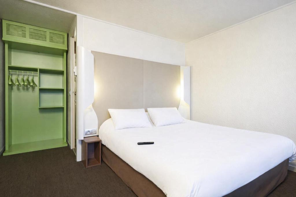 a bedroom with a large white bed and a green door at Campanile Lens in Lens