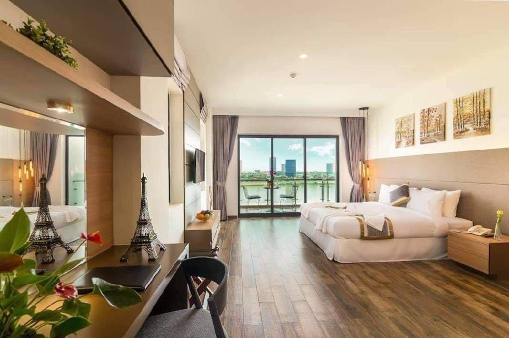 a large hotel room with a large bed and a desk at The Westerly Riverside Hotel in Phnom Penh
