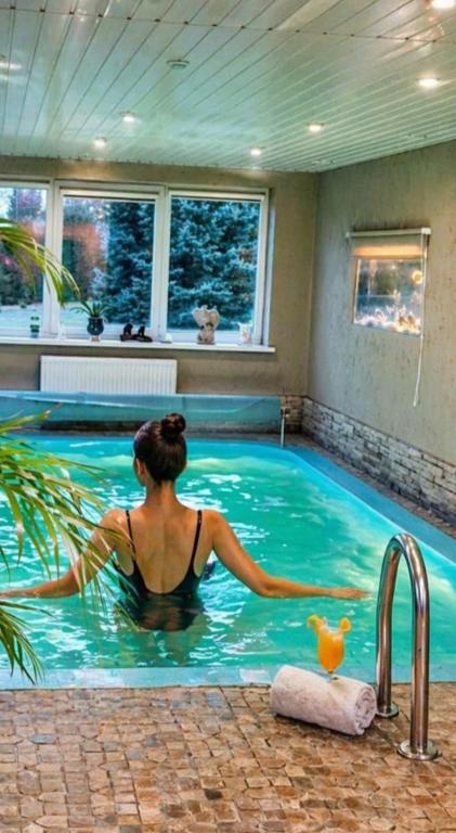 a woman is sitting in a swimming pool at Pavasario Namai & SPA in Alytus