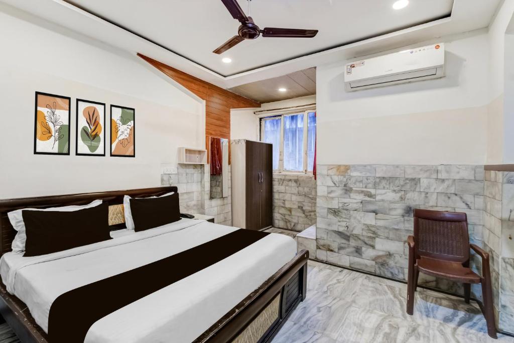 a bedroom with a bed and a chair at Super Hotel O MG Road Raniganj Formerly Holiday Hotel in Hyderabad