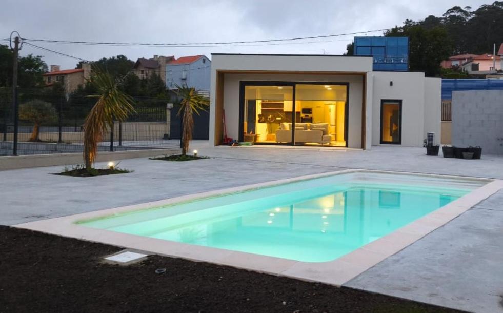 a swimming pool in front of a house at Casa O OLIVO in Boiro