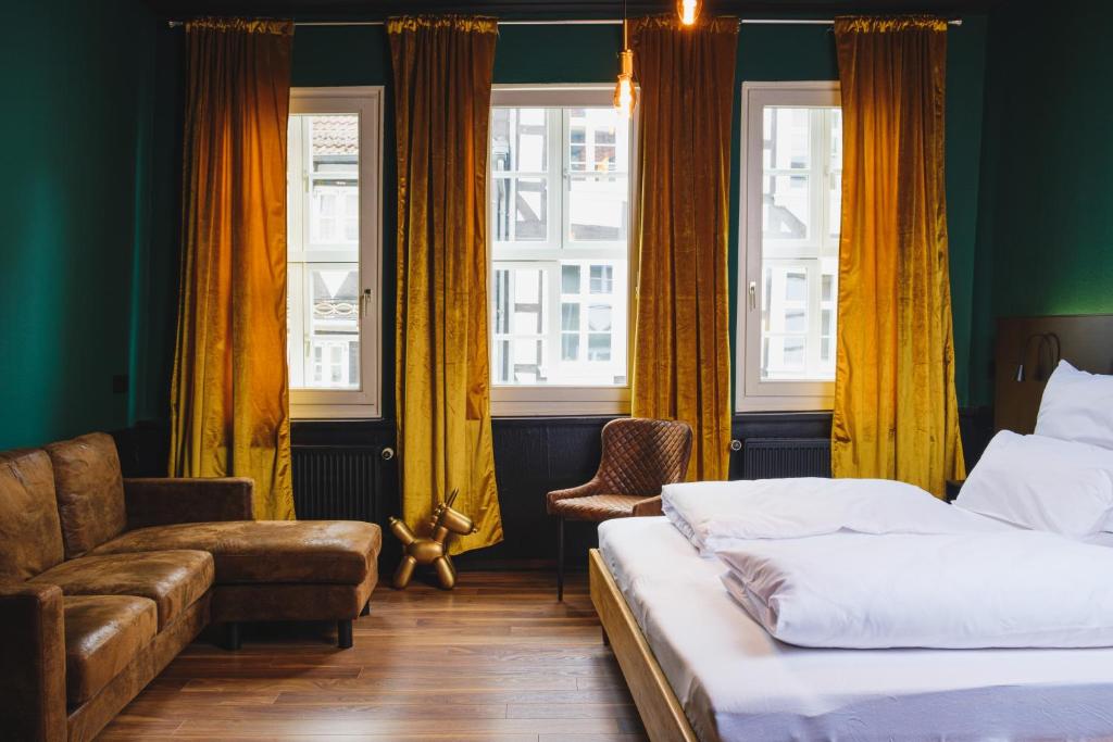 a bedroom with two beds and a couch and windows at friedrich DAS BETT in Braunschweig