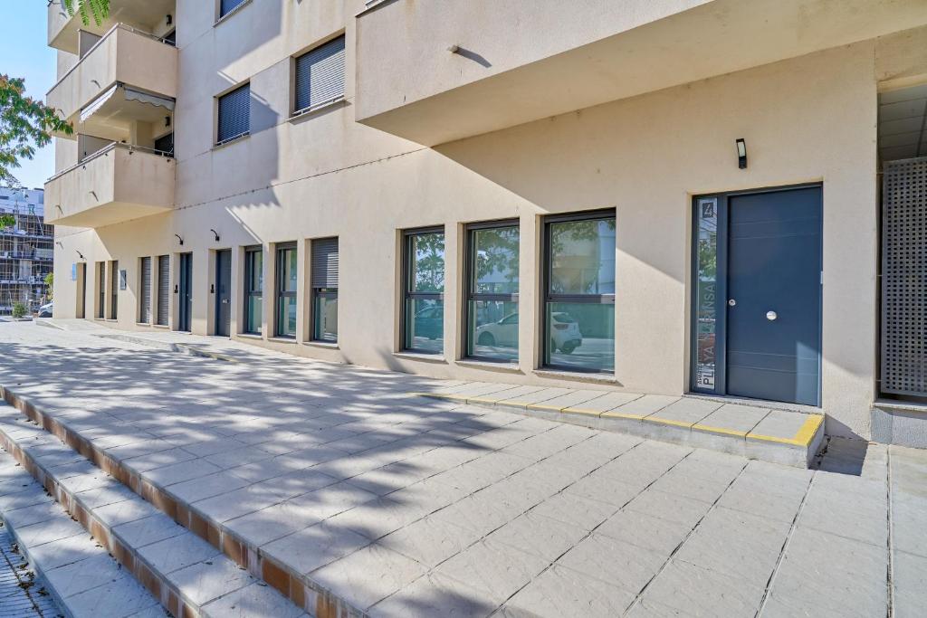 a building with large windows on a sidewalk at Aptos Turísticos Playa Marinsa in Torre del Mar