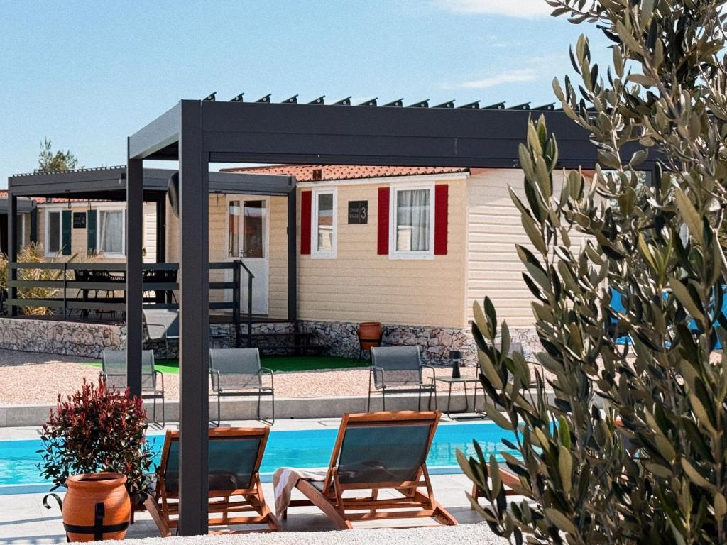 a pergola over a pool with chairs and a house at Auto-kamp Dvije suze 2 in Brištane