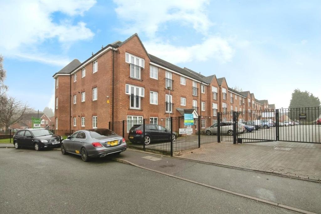 two cars parked in front of a brick building at Private Room in a shared flat with own Bathroom and Parking in West Bromwich