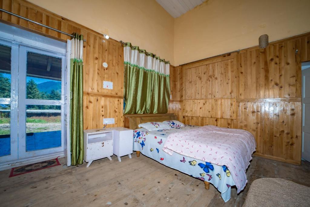 a bedroom with a bed with wooden walls and a window at Forest Rest House Gahan in Bāgi