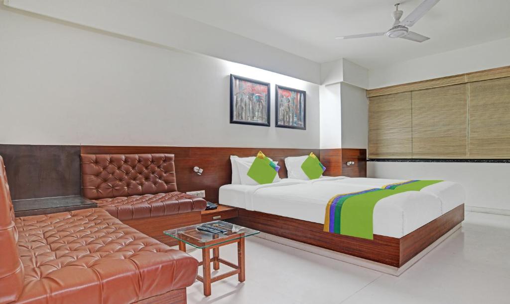 a bedroom with a bed and a couch at Treebo Cherry Tree in Indore
