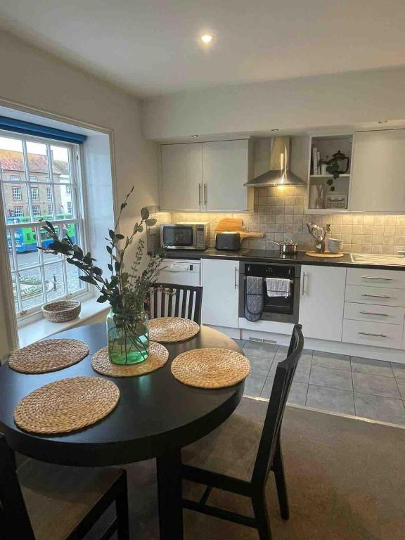 a kitchen with a black table with chairs and a kitchen with a counter at Large town centre apartment with parking in Wallingford
