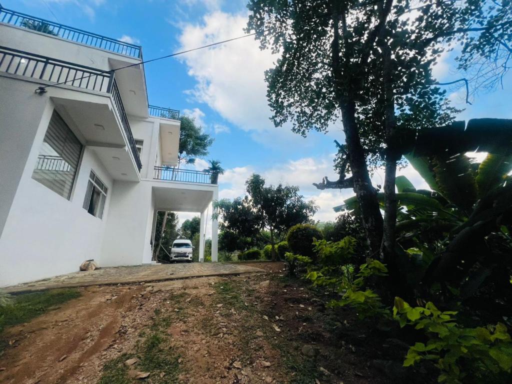 a house with a car parked in the driveway at Emerald Leaf Kandy Villa in Panabokka