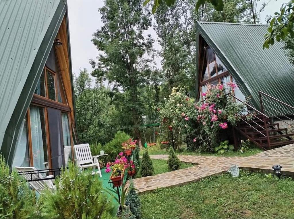 a house with a green roof and a wooden deck at Poienița Lupului in Vărbilău