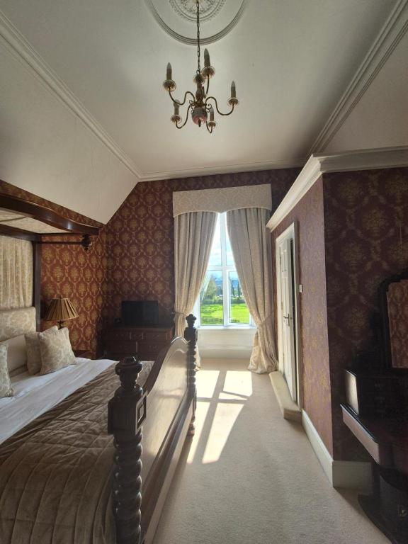 a bedroom with a bed with a chandelier and a window at Glenduff Manor in Glendiff
