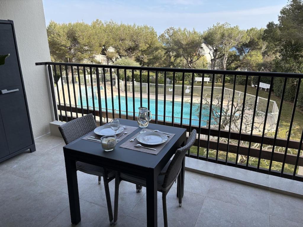 a table on a balcony with a view of a pool at Superbe studio terrasse piscine et plage in Fréjus