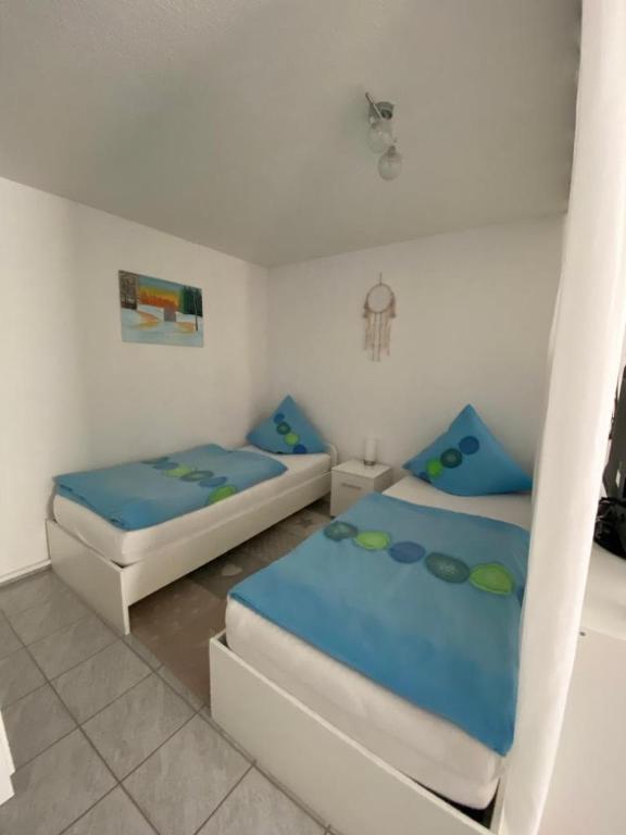two beds in a white room with blue sheets at Appartement Linda in Rheinfelden