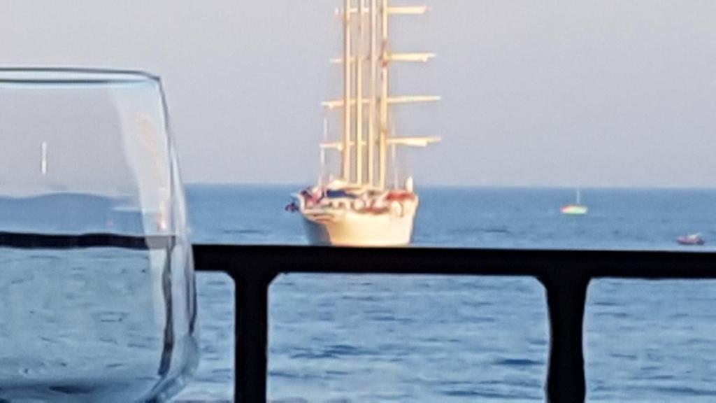 ジャルディーニ・ナクソスにあるLoft Profumo di Mareの海辺の手すりに座るグラスワイン