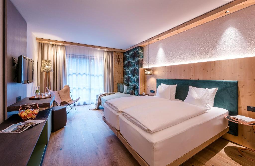 ザンクト・アントン・アム・アールベルクにある"Quality Hosts Arlberg" Hotel zur Pfeffermühleの大型ベッドとテレビが備わるホテルルームです。