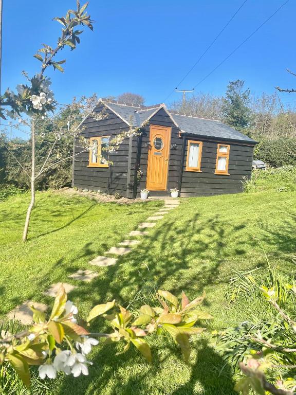 a house with a wooden door in a yard at The Orchard Cabin in Cardington