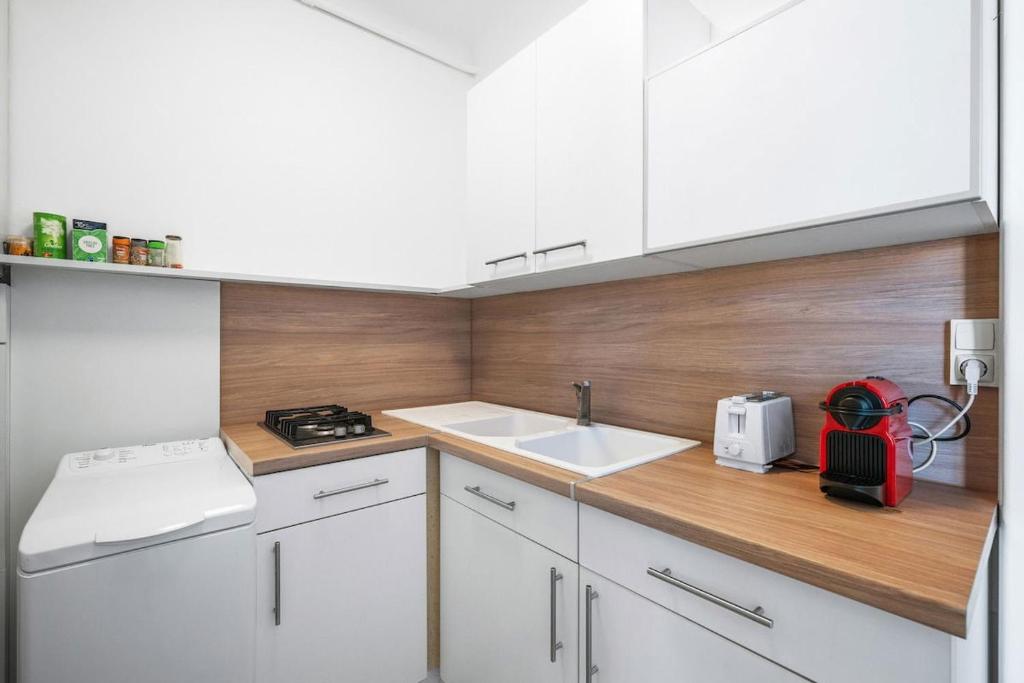 a kitchen with white cabinets and a red appliance at LE FELIX FAURE - Hyper Centre - Terrasse - Plages in Menton