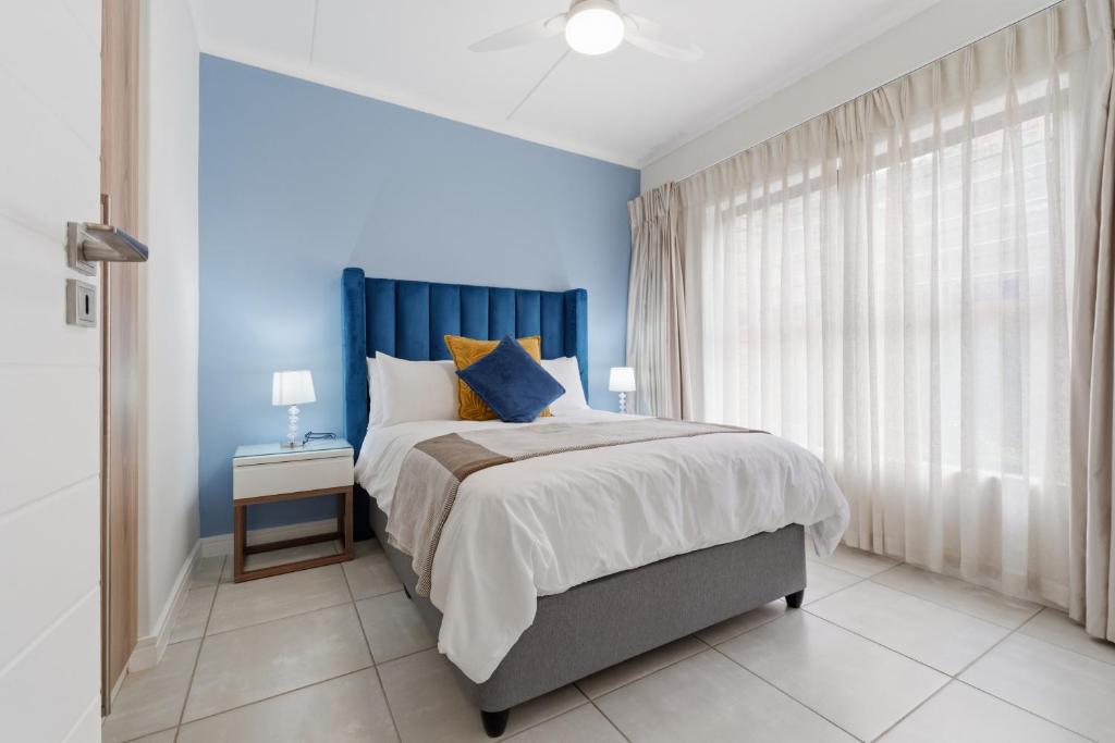 a blue bedroom with a bed and a window at Ballito Hills 171 in Ballito