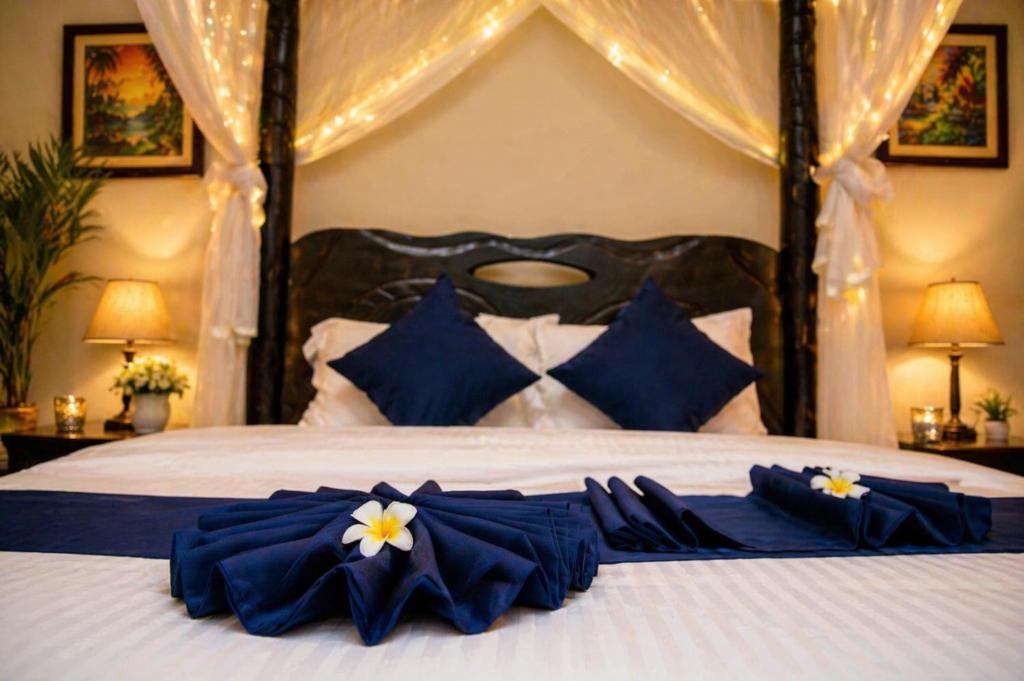 a bed with blue and white pillows on it at Kaliba Beach - Rutsiro in Rutsiro