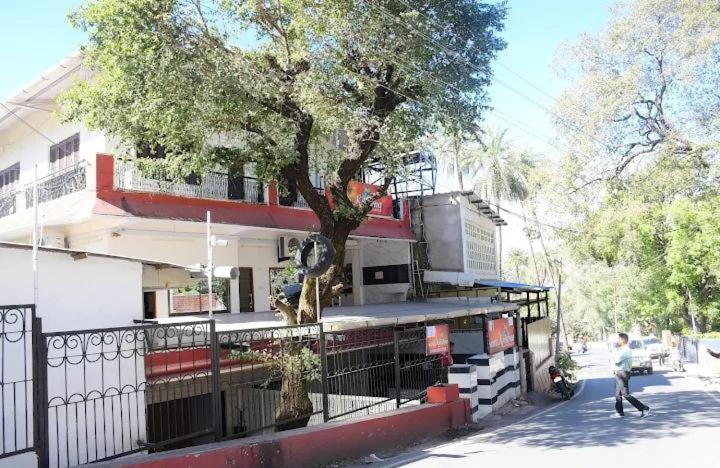 a man walking in front of a building with a tree at zoz mount abu in Jāmb