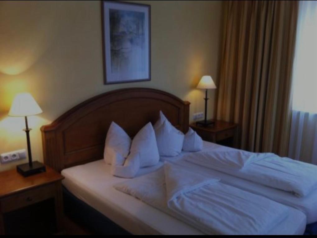 a bedroom with a bed with white sheets and pillows at Hotel La Strada & Sultan in Murnau am Staffelsee