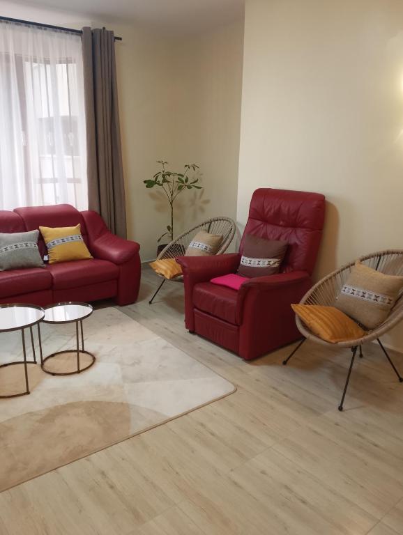 a living room with two red couches and chairs at Kwame Homes in Nakuru