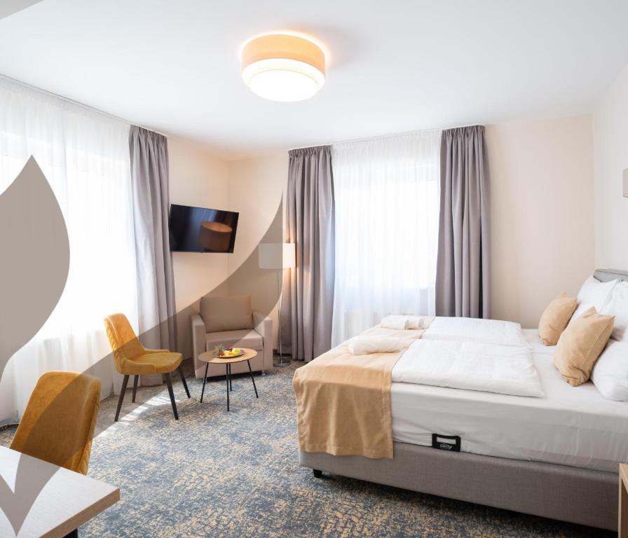 a hotel room with a bed and a table and chairs at Kikelet Club Hotel in Miskolctapolca