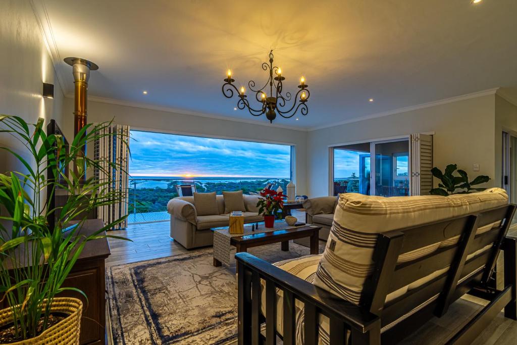 a living room with a chandelier and a large window at Whales Rest in Pearly Beach