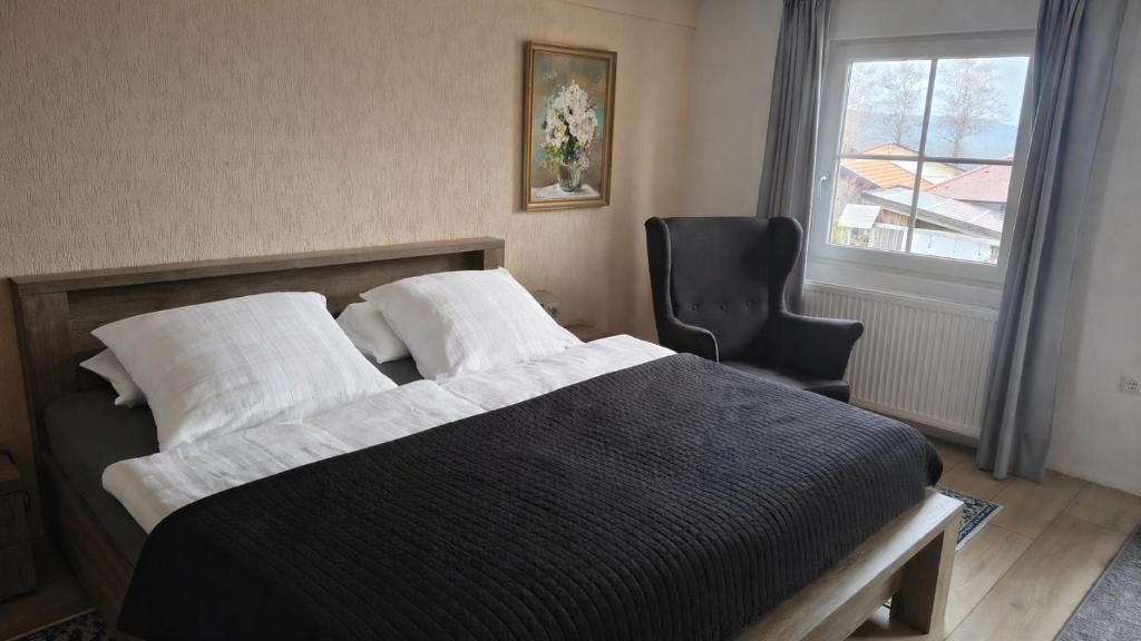 a bedroom with a bed and a chair and a window at Ferienwohnung Eleni in Mauth