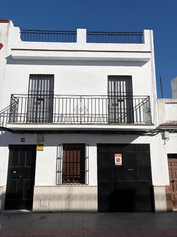 a white building with black doors and a balcony at Casa en la Huertecilla in Lora del Río