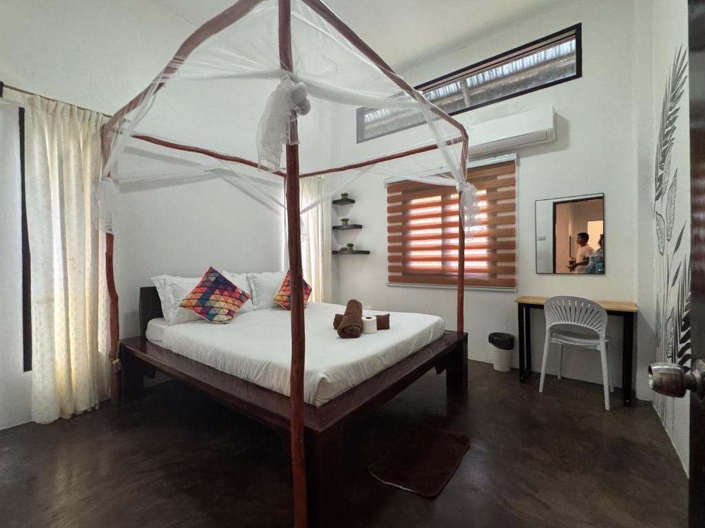 a bedroom with a canopy bed and a desk at Nutmeg Cottage SIARGAO 2BR exclusive whole house in General Luna