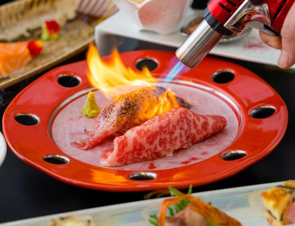 ein Teller mit Essen und einem Stück Fleisch, das brennt in der Unterkunft Hotel Ryutouen in Saga