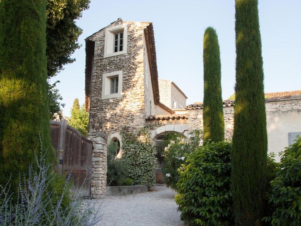 an old stone house with a gate and trees at Domaine Les Martins in Gordes