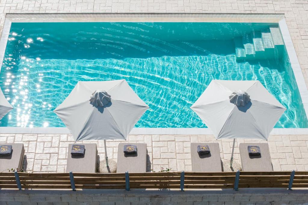 a painting of a swimming pool with two white umbrellas at Villa Kouros P&A in Áfra