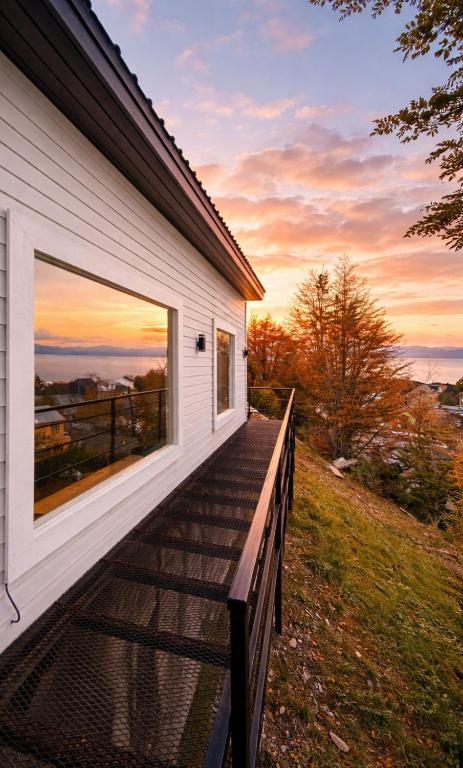 a house with a deck with a sunset in the background at CIELO AUSTRAL house overlookin the ocean in Ushuaia