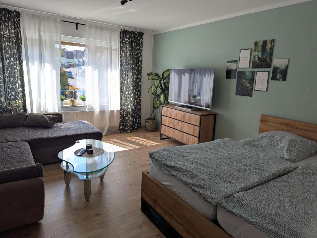 a living room with a couch and a tv at Ferienwohnung Rosenbaum in Rannungen